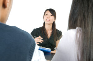 A woman talking to a couple and holding a clipboard