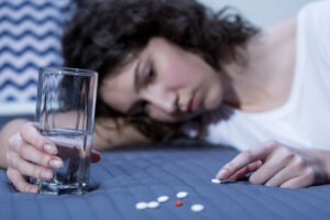 Shot of a young girl laying on a bed and counting pills
