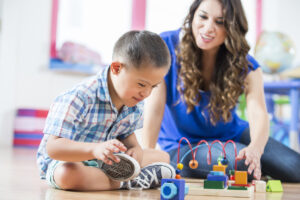 Hispanic Down Syndrome boy reaching for toys at daycare center