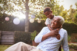 Young black boy embracing grandfather sitting in garden