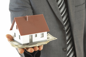 businessman holding mini house and Us dollars, shallow dof