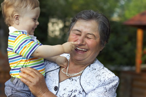 cute grandson grabbing the nose of laughing great grandmother. funny outdoors