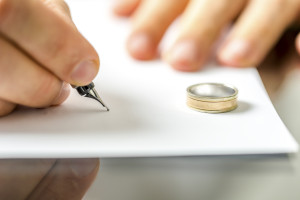 Closeup of male hand signing divorce papers.